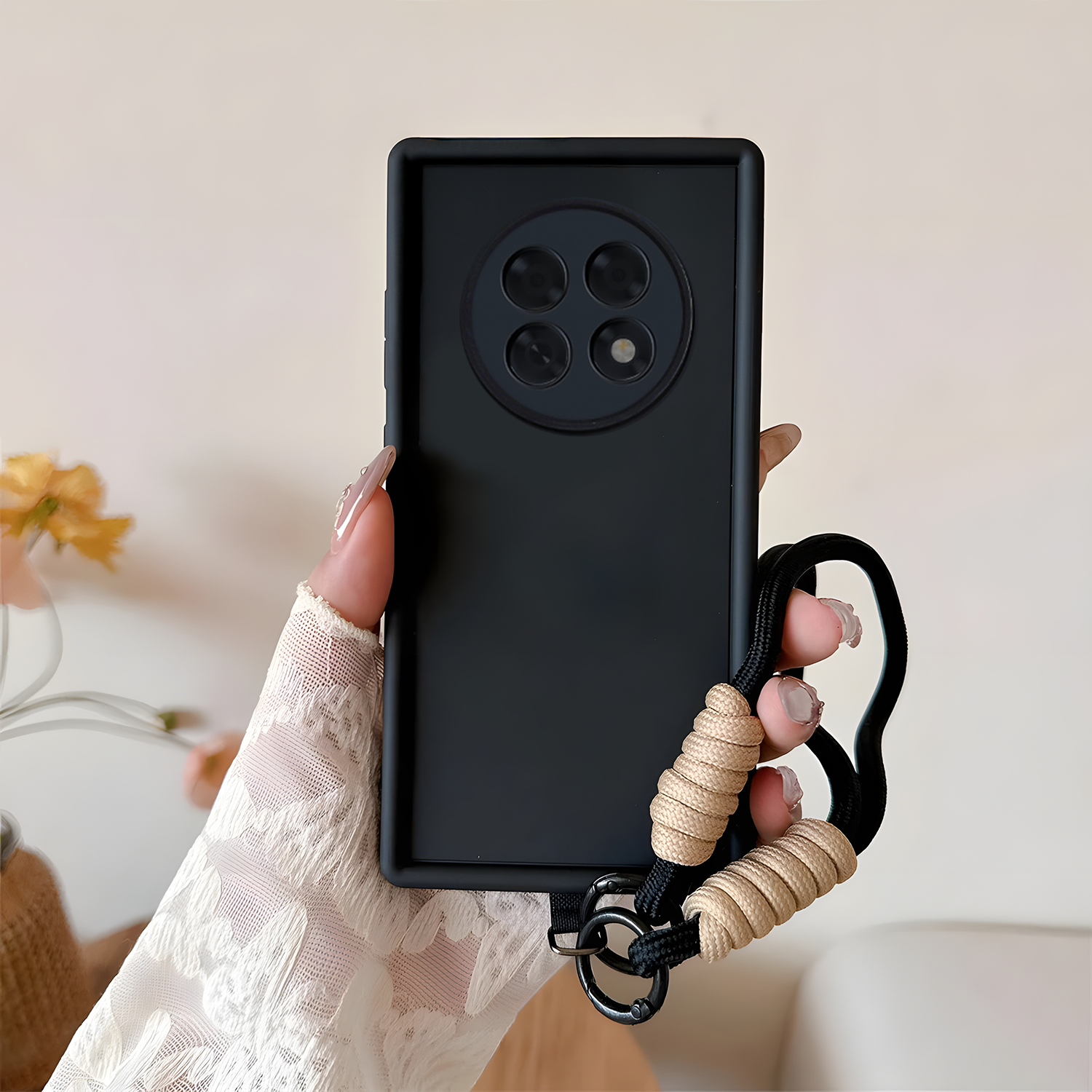 Oppo F31 Pro Plus 5G Black phone case with a beige rope handle held by a hand against a blurred indoor background