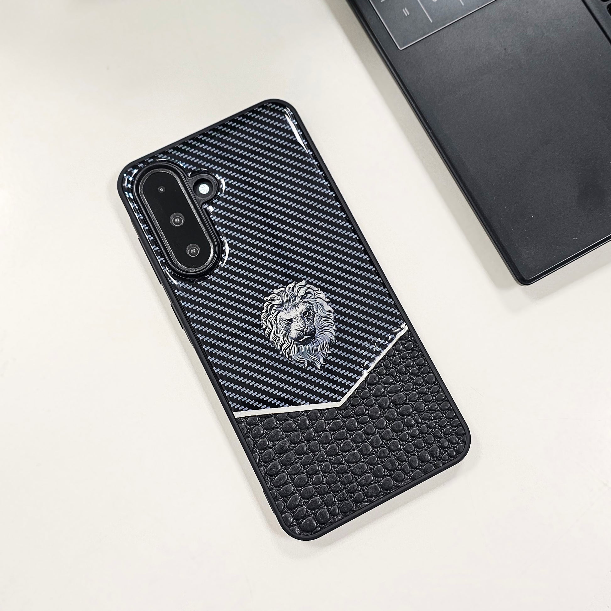 Black textured phone case with a lion emblem on a light gray surface