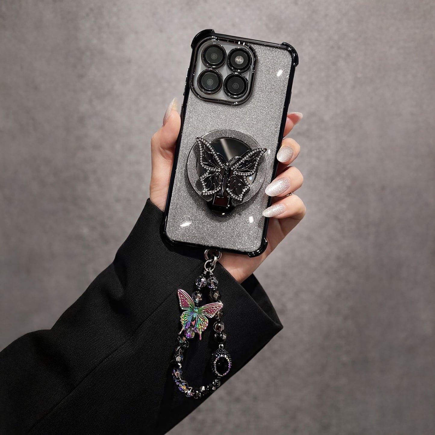 Hand holding a Motorola Edge 60 Pro 5G phone case with a butterfly design and charm on a gray background