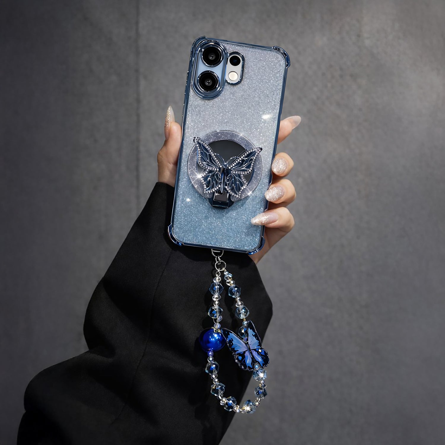 Vivo V60 5G Phone case with butterfly design and dangling charms held by a hand against a dark background