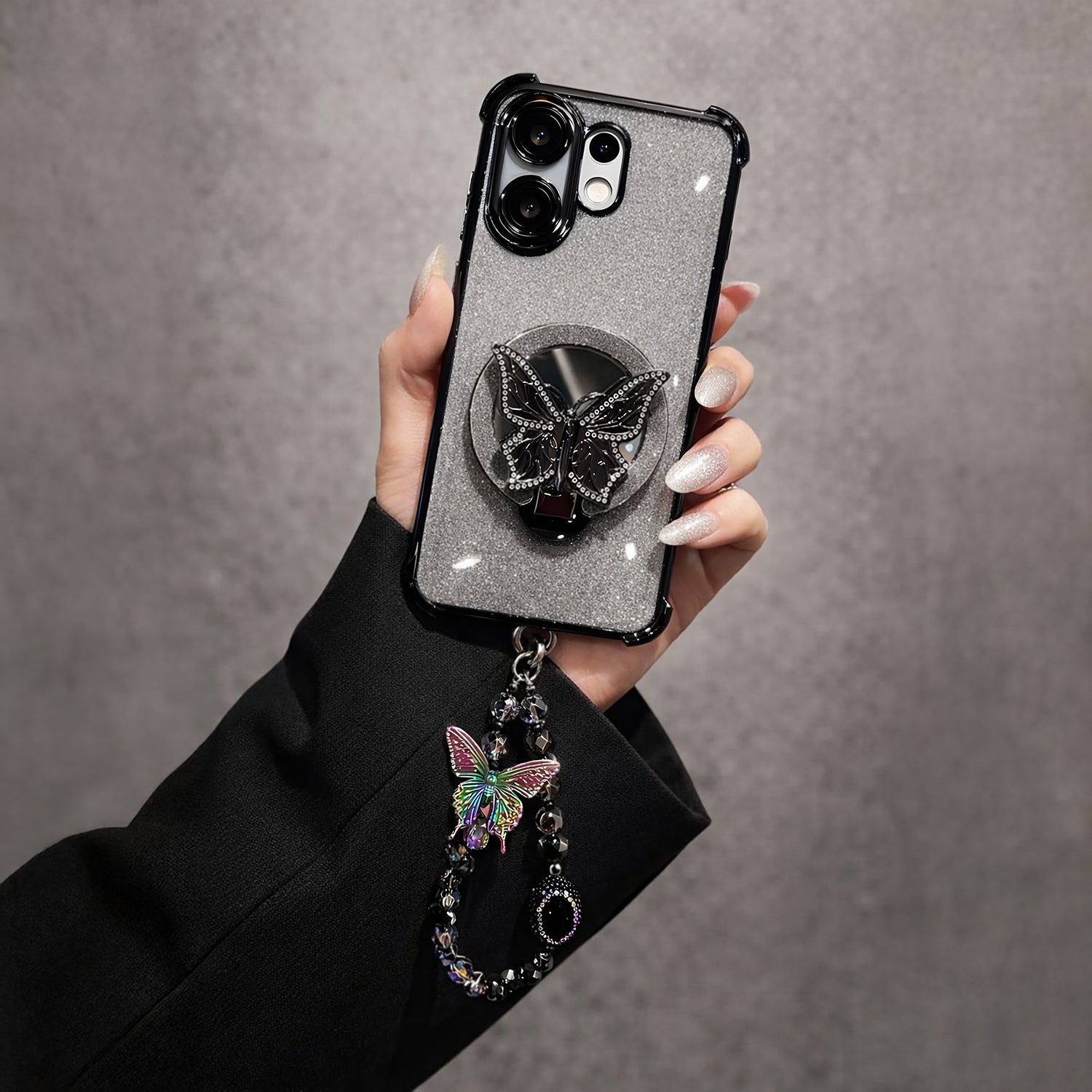 Vivo V60 5G Hand holding a phone case with a butterfly design and decorative chain against a gray background